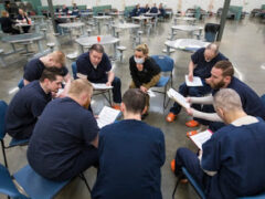 Inmates in the drug treatment program sitting in chairs in a circle, each looking at a notebook