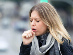 Woman coughing outdoors